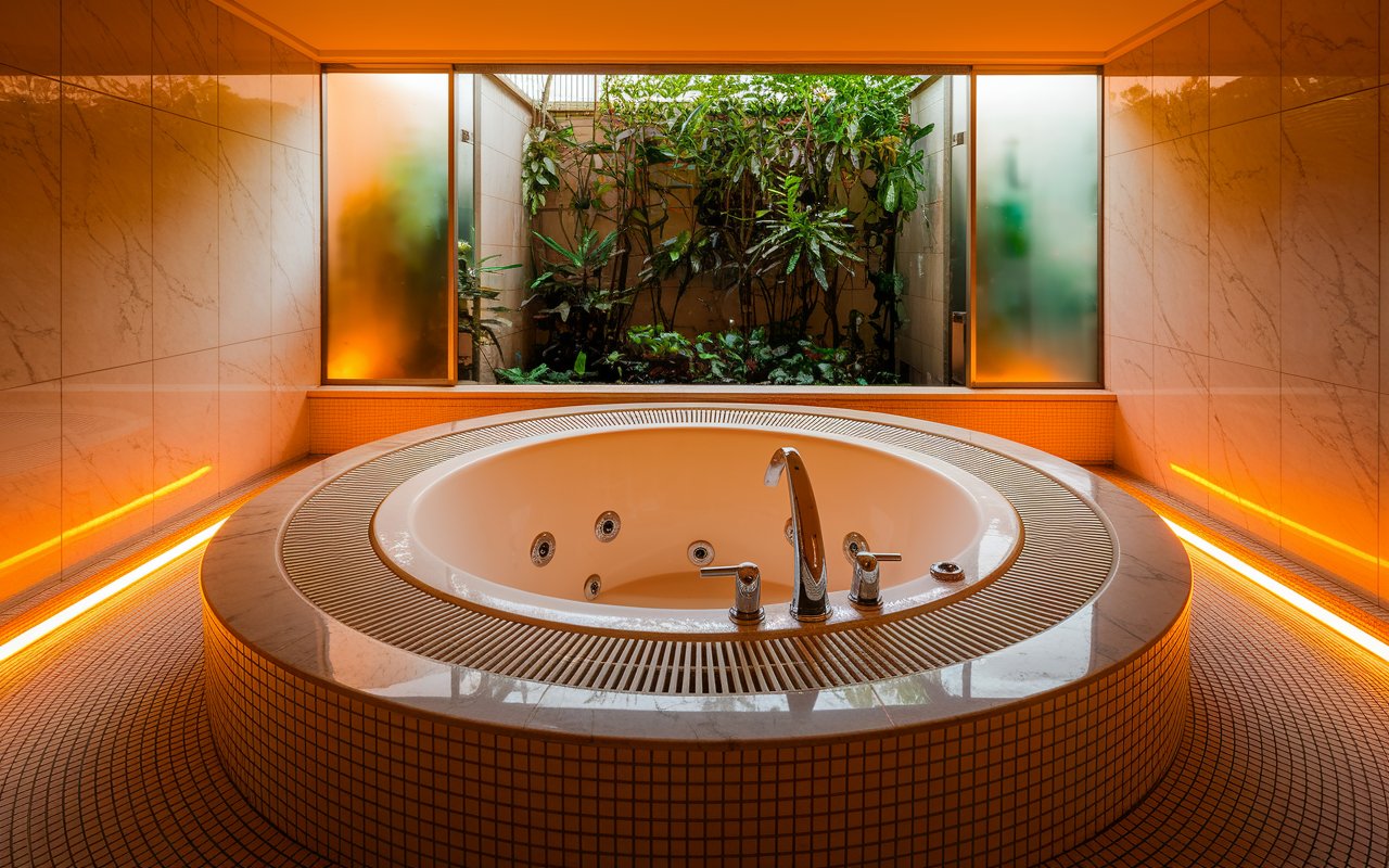 A spacious bathroom featuring a large tub and a bright window, inviting natural light into the serene space.