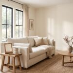 Realistic living room with warm Swiss Coffee off-white walls, natural light, neutral decor, wood flooring, and paint swatches for a paint color review.