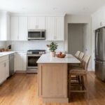 Modern kitchen with white cabinets, quartz countertops and stainless steel appliances.